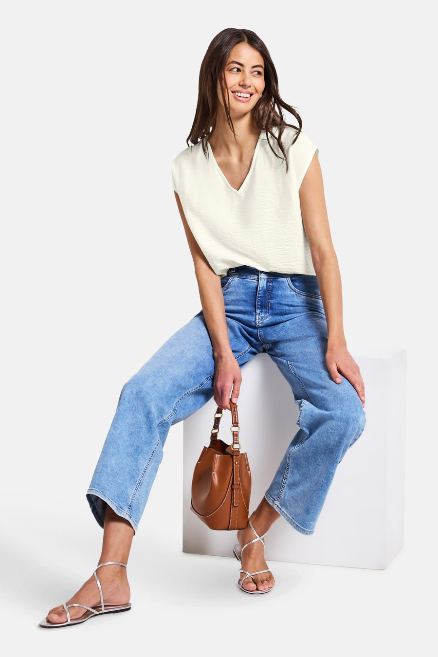 Mouwloos wit overhemd van Street One, gedragen met een wijde jeans en zilveren sandalen.