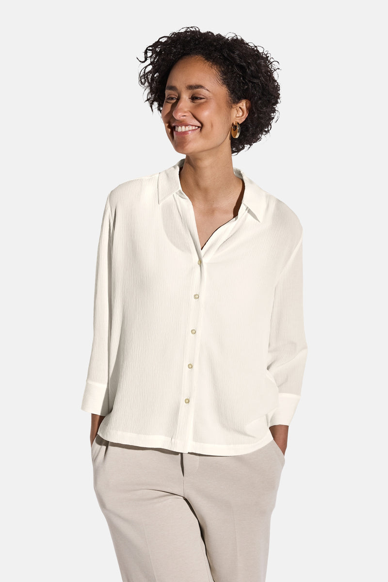 Chemisier blanc à manches longues de Street One, avec une texture plissée, porté avec un pantalon beige.
