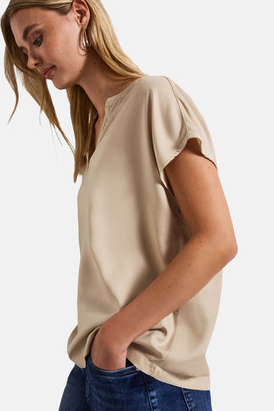Beige blouse met korte mouwen van Street One, gedragen met een spijkerbroek en gouden oorbellen.