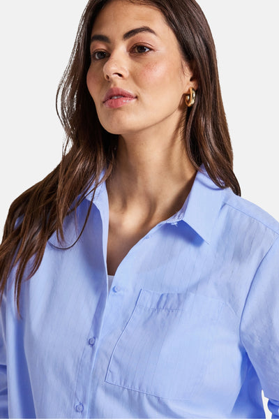 Blauwe blouse met lange mouwen van Street One, subtiele strepen, gedragen met gouden oorbellen.
