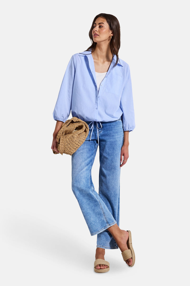 Blauwe blouse met lange mouwen van STREET ONE, gedragen met een witte tanktop, een spijkerbroek en gevlochten sandalen.