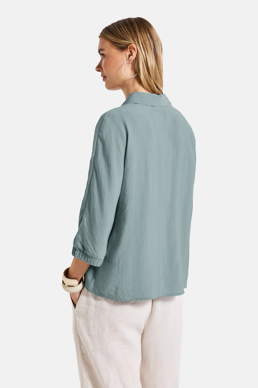 Blauwe blouse met lange mouwen van STREET ONE, met ivoorkleurige armband en zilveren oorbellen.
