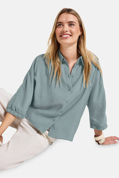 Blauwe blouse met lange mouwen van Street One, gedragen met een beige broek en zilveren oorbellen.