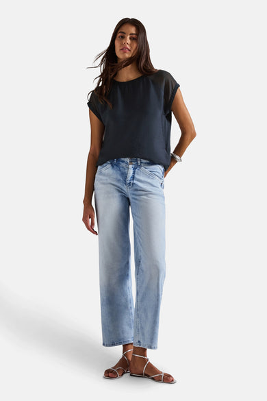 Blauwe blouse met korte mouwen van Street One, gedragen met een wijde jeans en zilveren sandalen.