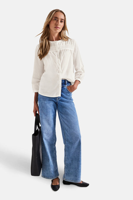 Wit overhemd met lange mouwen van Street One, gesmokte details bij de halslijn, gedragen met een wijde jeans en ballerina's.
