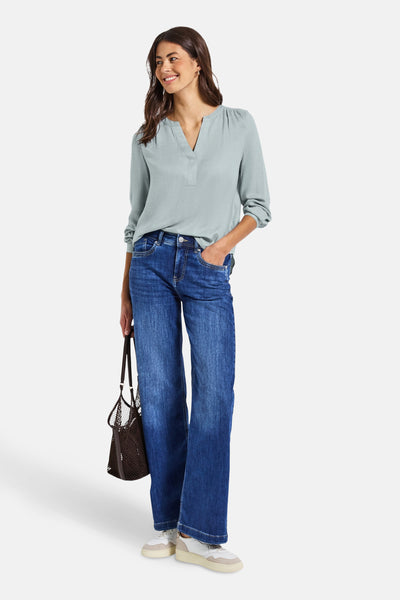 Blauwe blouse met lange mouwen van Street One, gedragen met een spijkerbroek en sneakers.