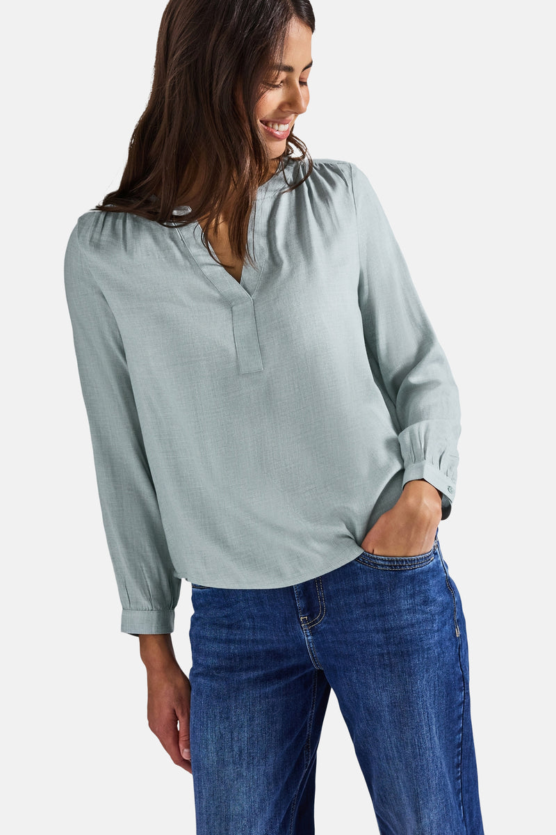 Blauwe blouse met lange mouwen van STREET ONE, gedragen met een spijkerbroek, hand in de zak.