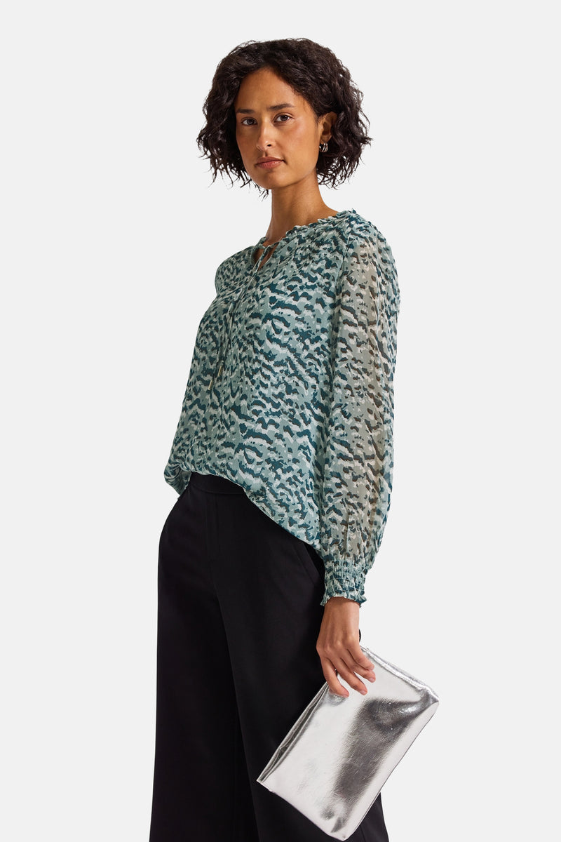 Multikleurige blouse met lange mouwen van STREET ONE, met een abstract patroon, gedragen met een zwarte broek en een zilveren clutch.