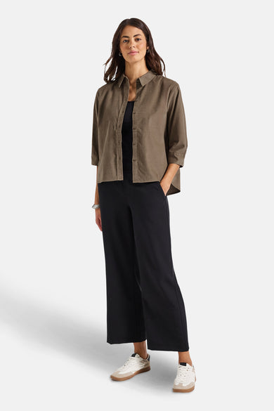 Chemisier beige à manches longues de Street One, porté avec un débardeur noir et un pantalon large.
