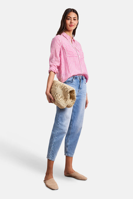 Chemise rose à manches longues de STREET ONE, rayée blanche, portée avec un jean bleu clair, des mules beiges et un sac en paille.
