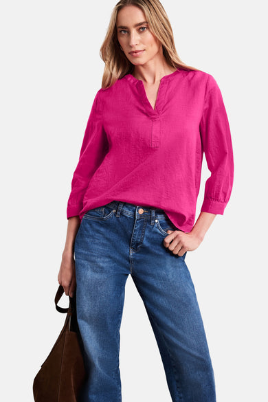 Blouse rose vif à col en V et manches 3/4 de STREET ONE, en tissu texturé, portée avec un jean.