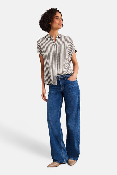 Multicolored short-sleeve striped blouse with button front, worn with blue wide-leg jeans and beige pointed-toe flats, full-length side view.