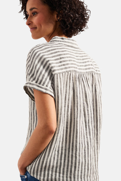 Multicolored short-sleeve blouse with vertical gray and white stripes, gathered back detail, side view on model wearing jeans