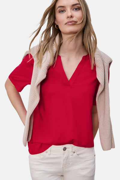 Rood overhemd met korte mouwen van STREET ONE, met V-hals, gedragen met een beige trui over de schouders en een witte broek.