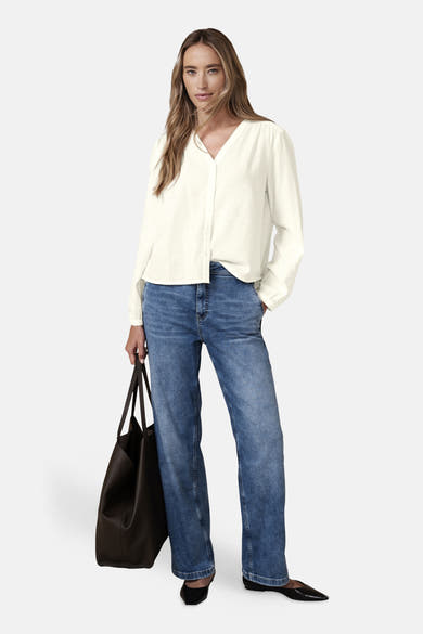 Chemisier blanc à manches longues de Street One, porté avec un jean bleu et un sac fourre-tout en cuir.
