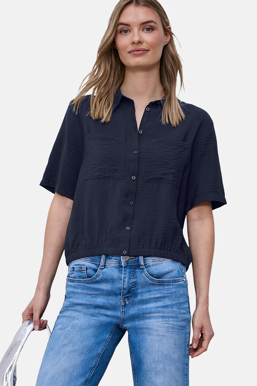 Blauw overhemd met korte mouwen van STREET ONE, getextureerd, gedragen met een spijkerbroek en een zilveren tas vasthoudend.