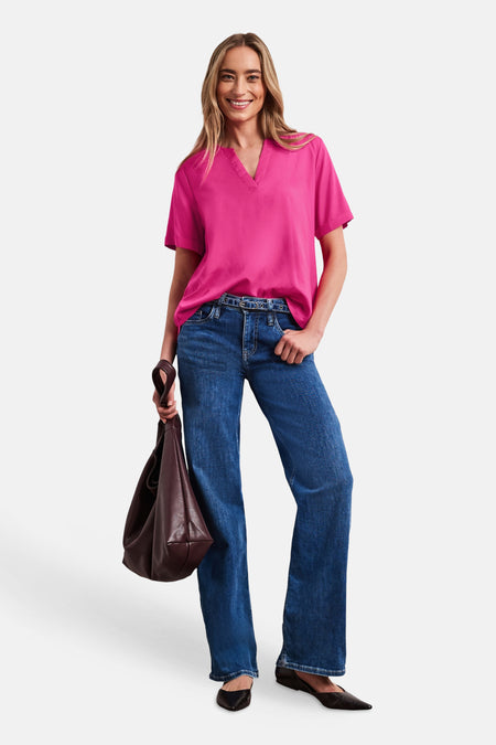 Blouse rose de STREET ONE à manches courtes et col en V, portée avec un jean bleu et un sac marron.