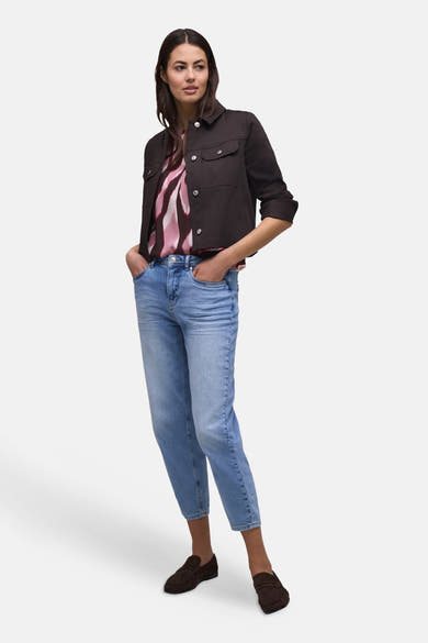 Multikleurige blouse van STREET ONE met abstract patroon in roze, framboos en wit, gedragen onder een bruin jasje en een spijkerbroek.