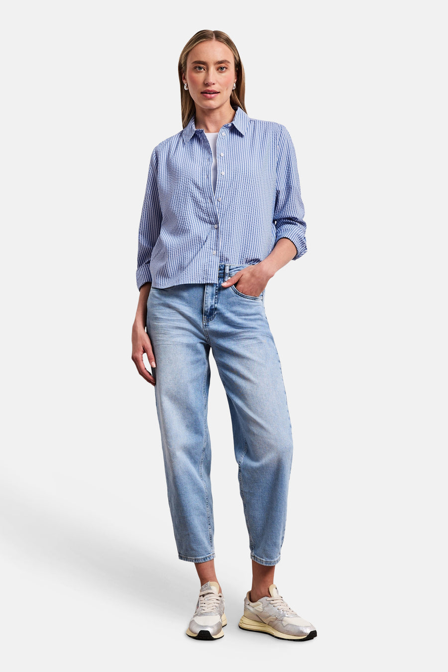Chemise seersucker à rayures bleues et blanches de STREET ONE, avec manches retroussées, portée avec un jean clair et des baskets.