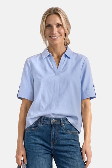 Light blue short-sleeve blouse with pointed collar and rolled cuffs, worn with dark denim jeans, front view
