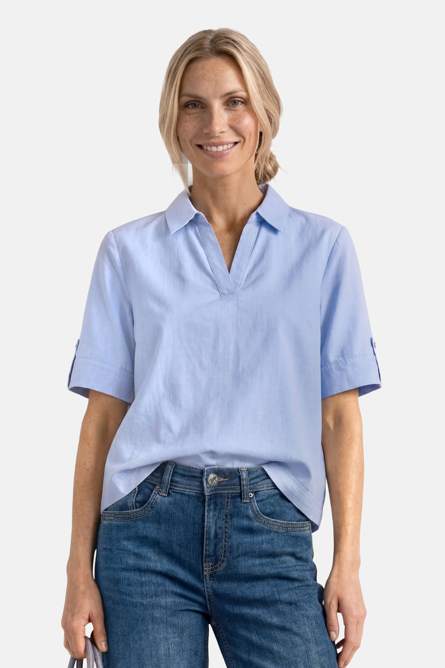 Light blue short-sleeve blouse with pointed collar and rolled cuffs, worn with dark denim jeans, front view