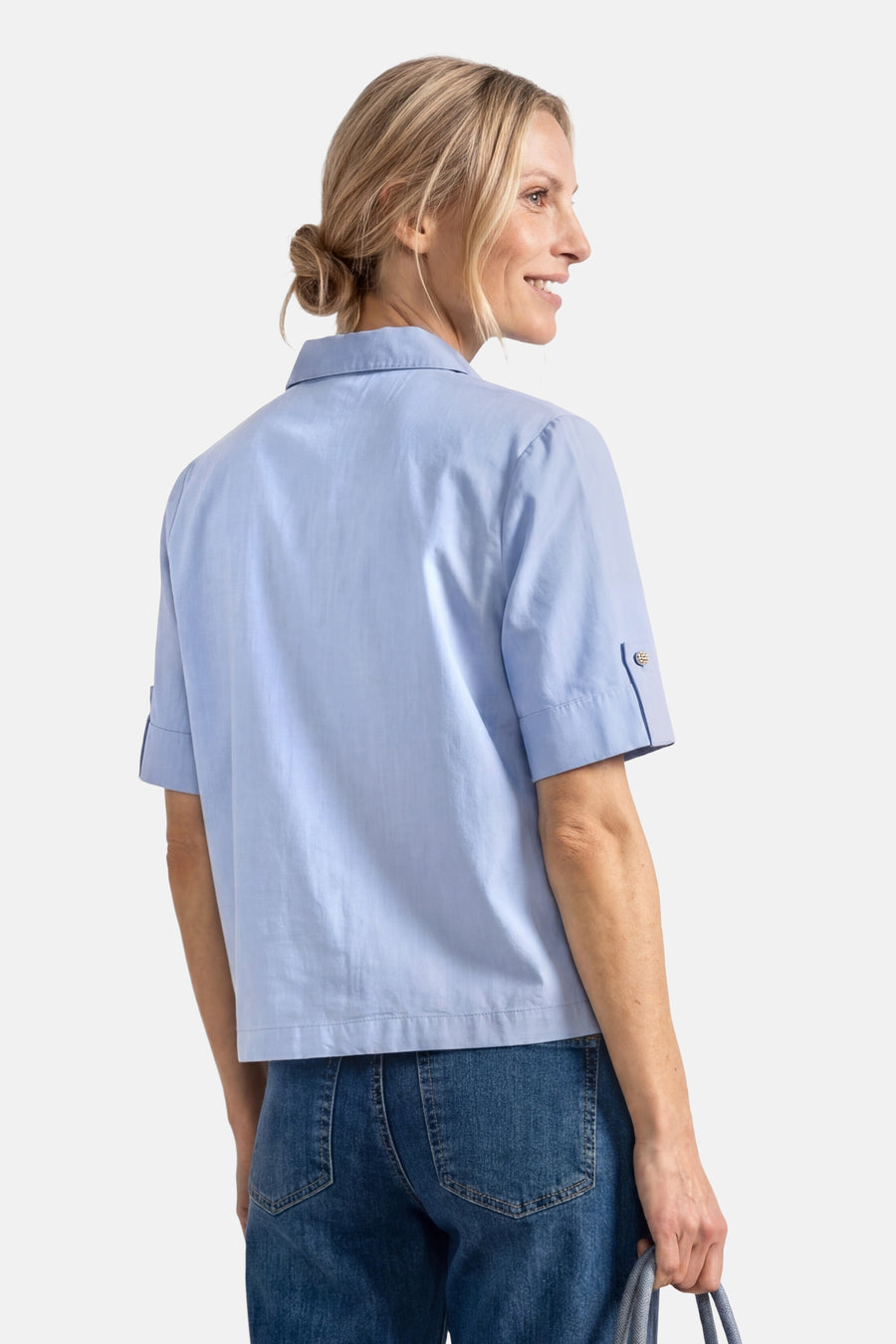 Light blue short-sleeve blouse with buttoned cuffs, shown from back on model wearing jeans.