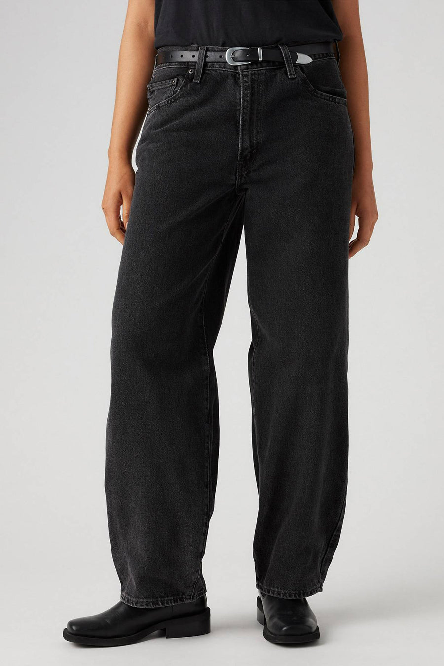 Jean droit en denim gris foncé de Levi's, porté avec une ceinture en cuir noire et des chaussures noires.