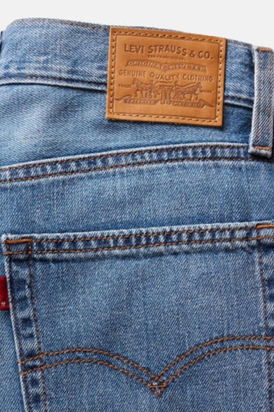 Jean droit bleu en denim de Levi's®, avec étiquette marron en cuir à l'arrière.
