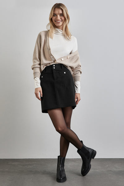 Jupe courte noire de STREET ONE, portée avec un cardigan beige et des bottines noires.
