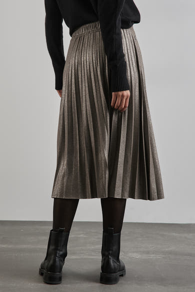 Beige geplooide lange rok van STREET ONE, gedragen met zwarte panty en enkellaarsjes, van achteren gezien.