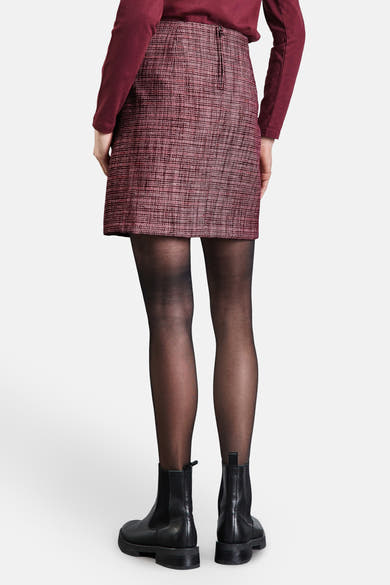 Jupe courte bordeaux by Street One, à motif texturé, portée avec des collants noirs et des bottines noires.