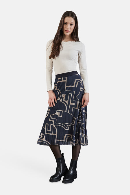 Lange veelkleurige rok van Street One, met grafische print, gedragen met een beige top, zwarte panty en enkellaarsjes.