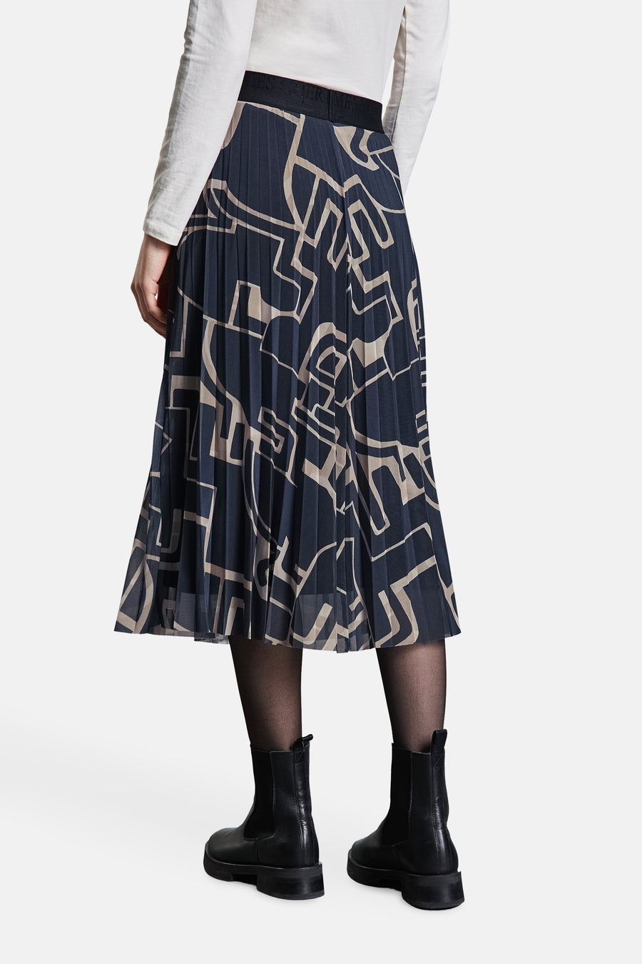 Gestreepte lange rok van Street One in meerdere kleuren, met geometrische patronen, gedragen met een witte top, zwarte panty en zwarte enkellaarsjes.