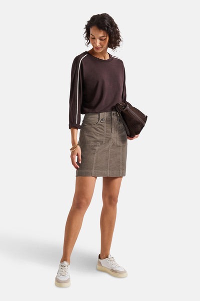 Korte beige ribfluwelen rok van Street One, gedragen met een bruine trui en witte sneakers.