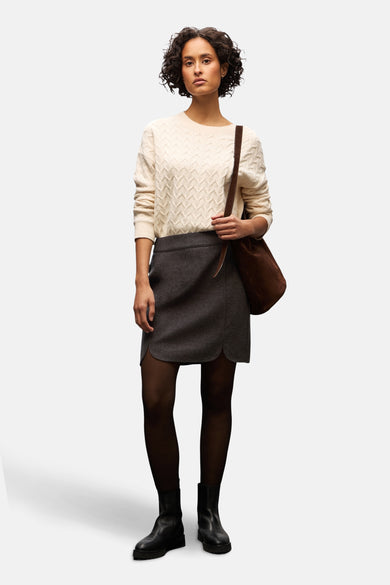 Jupe courte brune de STREET ONE, style classique avec ourlet arrondi, portée avec des collants noirs et des bottines en cuir.