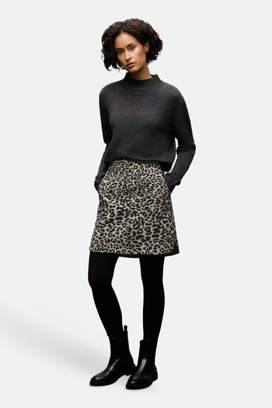 Jupe courte à motif léopard multicolore de Street One, portée avec un pull gris, des collants noirs et des bottines noires.