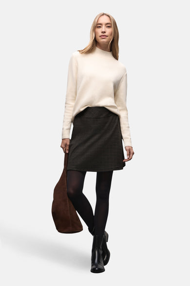 Jupe courte à carreaux de Street One, portée avec un pull blanc et des bottines noires.