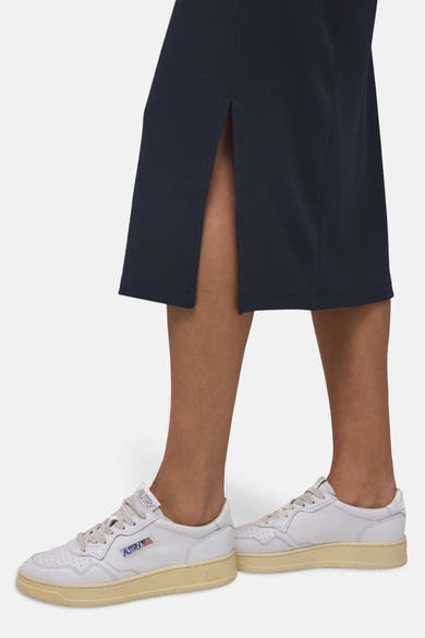 Jupe midi bleue de STREET ONE, avec une fente latérale, portée avec des baskets blanches.
