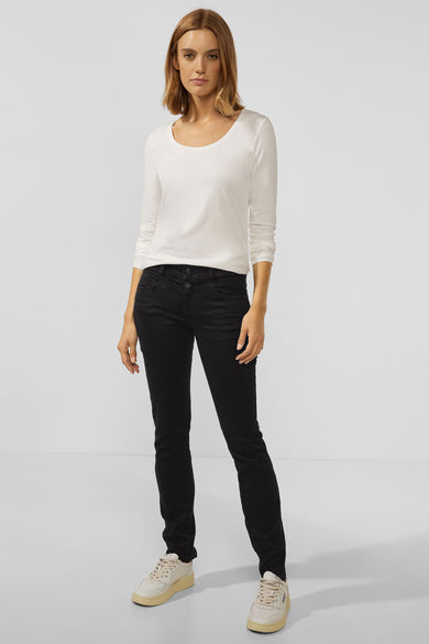 Jean slim noir en denim de Street One, porté avec un haut blanc à manches longues et des baskets beiges.