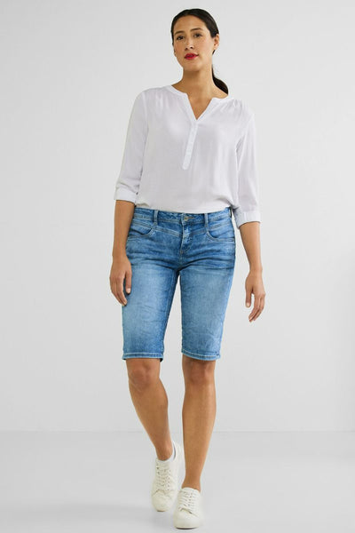 Bermuda court bleu de Street One, porté avec une chemise blanche à manches trois-quarts et des chaussures blanches.