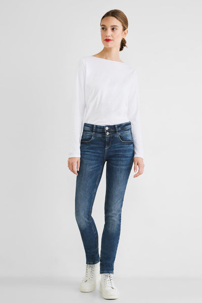 Slim-fit blue jeans with faded wash and classic five-pocket design, worn with white top and sneakers, front view