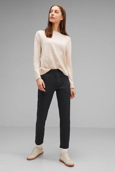 Pantalon noir de STREET ONE, porté avec un pull beige et des chaussures de sport couleur crème.
