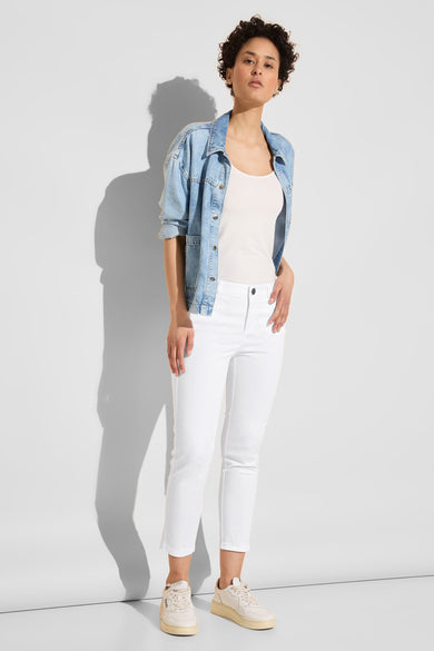 Pantalon coloré blanc de Street One, porté avec un débardeur blanc et une veste en jean.