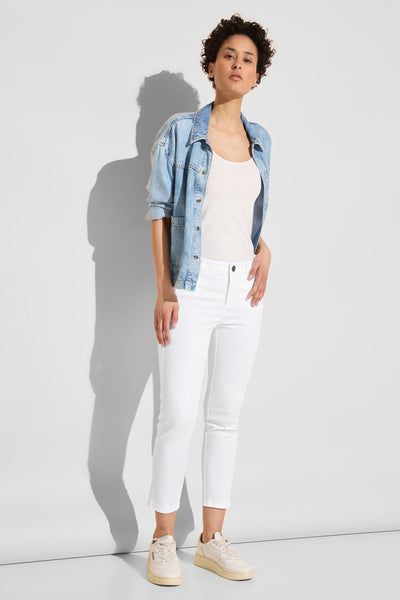 Pantalon coloré blanc de Street One, porté avec un débardeur blanc et une veste en jean.