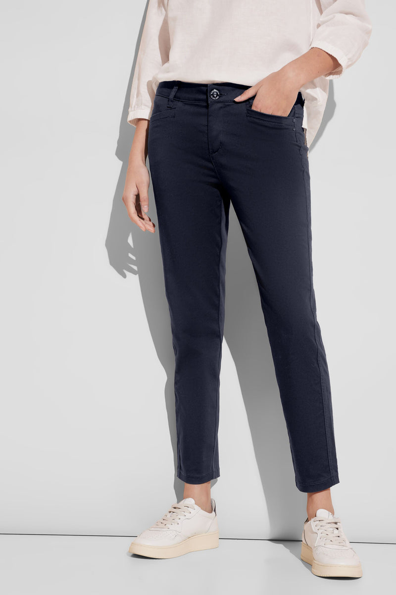 Pantalon coloré bleu de STREET ONE, porté avec un chemisier clair et des baskets blanches.