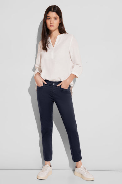 Pantalon coloré bleu de STREET ONE, porté avec un chemisier blanc et des baskets beiges.