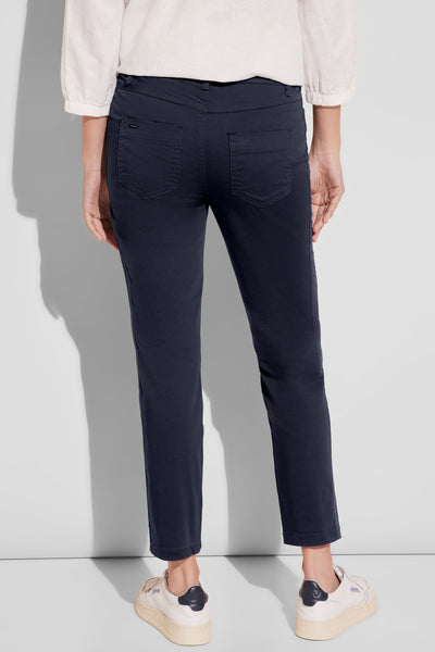 Pantalon coloré bleu de Street One, avec poches arrières et porté avec un chemisier blanc.