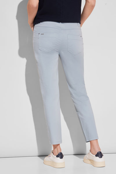 Pantalon coloré bleu de Street One, coupe droite avec poches arrières, porté avec des baskets blanches.
