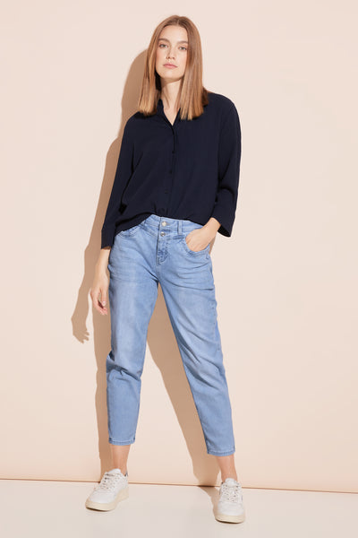 Jean Mom bleu clair de Street One, porté avec une chemise bleu marine et des baskets blanches.