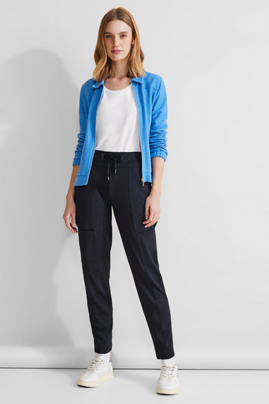 Pantalon cargo bleu de STREET ONE avec poches cargo, cordon de serrage à la taille et chaussures de sport blanches.
